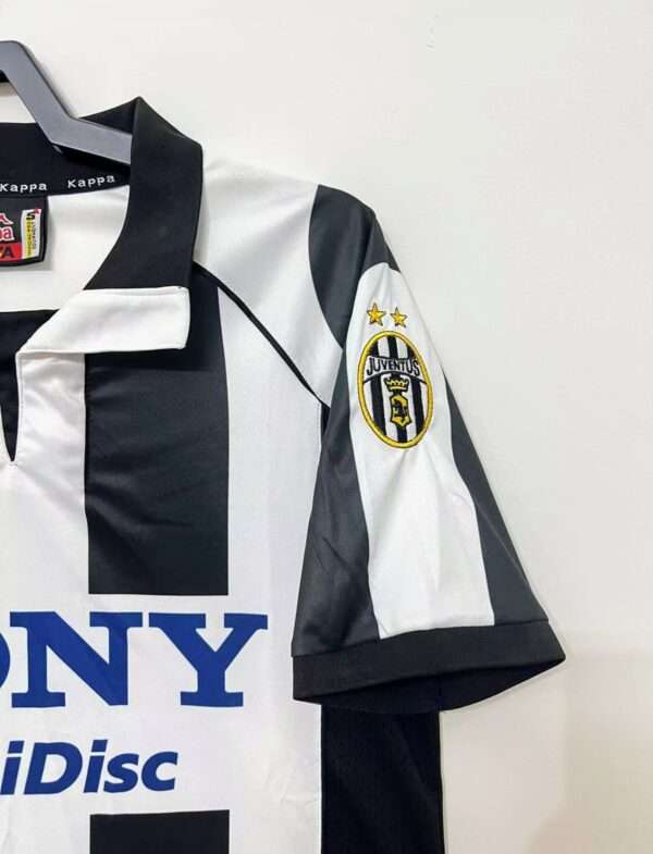 Présente la manche et col du maillot vintage Juventus Domicile 1997/1998
