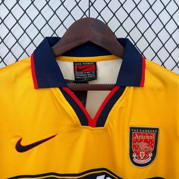 Présente le col et logos du maillot vintage Arsenal Extérieur 1997/1999