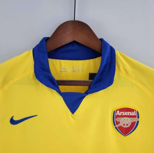 Présente le col et logos du maillot vintage Arsenal Extérieur 2003/2005
