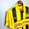 Présente la manche et col du maillot vintage Borussia Dortmund "Ligue des Champions" 2012/2013