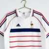 Présente les manches, col et logos du maillot vintage France Extérieur Coupe du Monde 1998