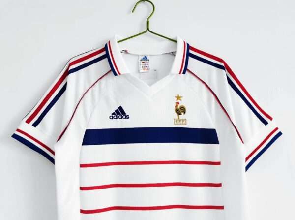 Présente les manches, col et logos du maillot vintage France Extérieur Coupe du Monde 1998