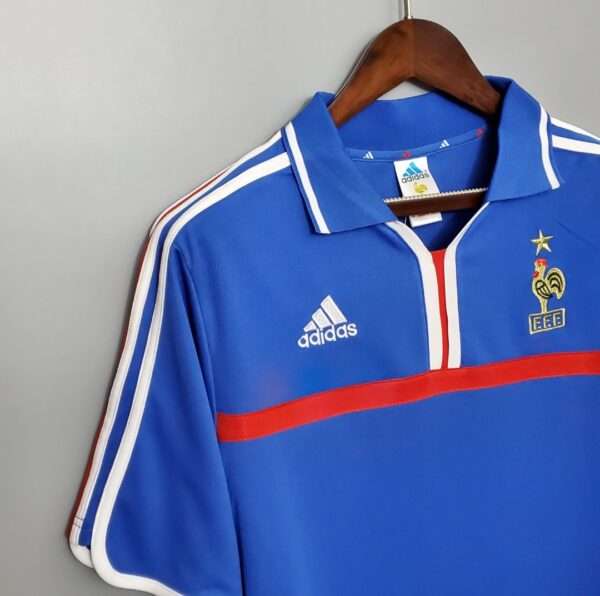 Présente la manche, col et logos du maillot vintage France Domicile Euro 2000