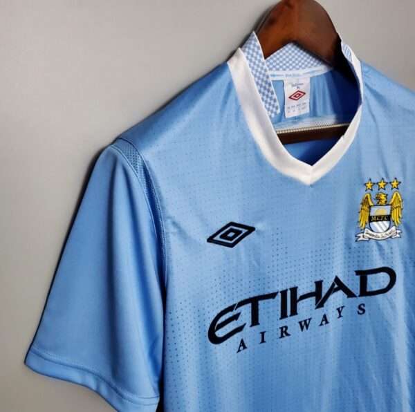 Zoom sur les logos, col et manche du maillot vintage Manchester City Domicile 2011/2012