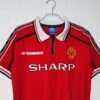 Présente le col, manches et logos du maillot vintage Manchester United Domicile 1998/2000