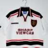 Présente les manches, col et logos du maillot vintage