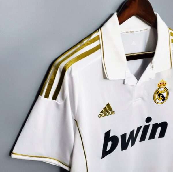 Présente la manche, col et logos du maillot Real 2011