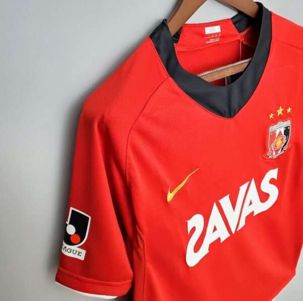 Présente le col, manche et logos du maillot vintage Urawa Red Diamonds Domicile 2008/2009