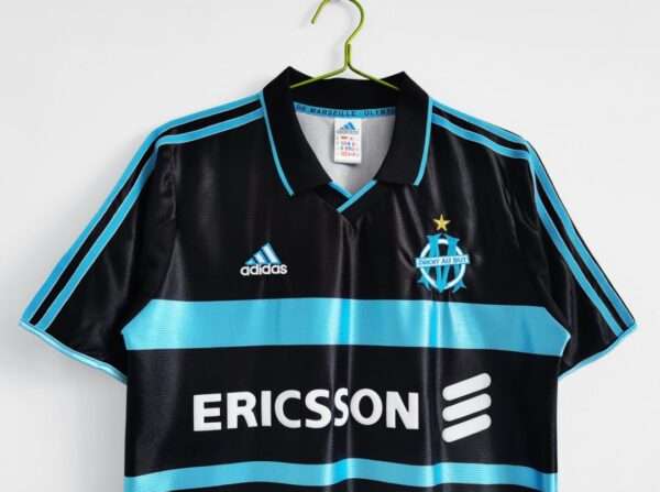 Présente les manches, col et logos du maillot vintage Olympique de Marseille "Troisième" 1999/2000